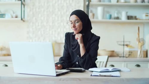 Woman Works on Laptop at Bright Kitchen Table
