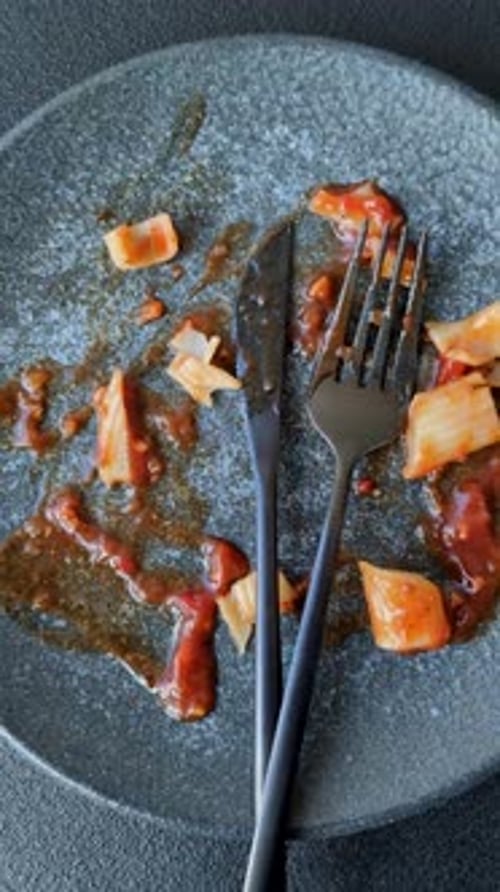 A dirty plate after a meal with leftover pasta and tomato sauce, cleaning. An empty dirty plate