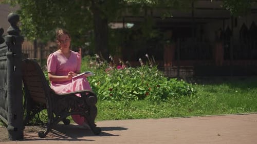 Serene Female Figure Relaxes on Park Bench with Book in Hand Tranquil Caucasian Woman in Rosy Dress