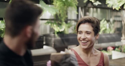 4k video footage of a young man surprising his girlfriend with a bunch of flowers at a cafe