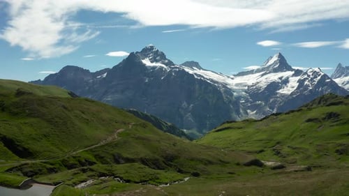 aerial view of beautiful mountain scenery with snow covered high mountain peaks and green grass duri