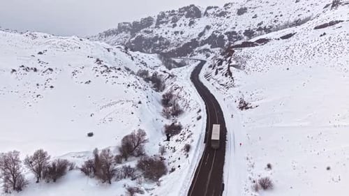 Aerial View of Truck Driving on Snow Covered Mountain Road