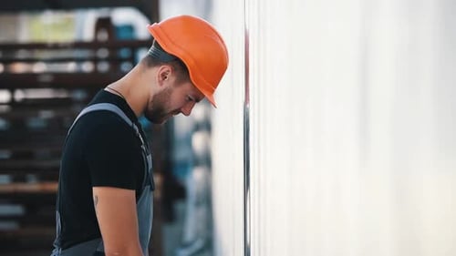 Young Man Leaning Against a Wall in Workplace