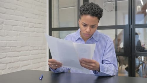Woman Reading Documents with Concerned Expression in Office