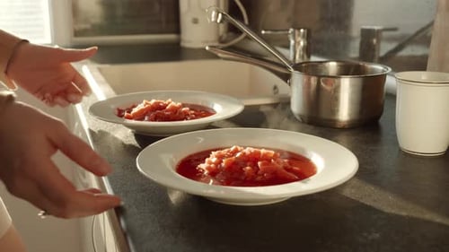 Closeup of woman serving dinner and taking two bowls with hot soup