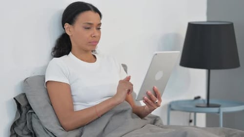 Woman Using Tablet While Relaxing in Bed
