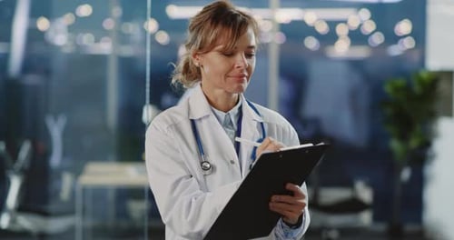 Woman Doctor Writing on Clipboard in Hospital Office