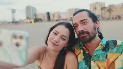 Close-up of romantic couple taking selfie on mobile phone while sitting on the beach