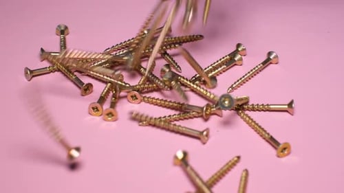 Gold Screws Falling Against Pink Background