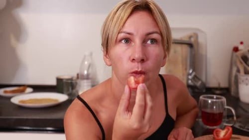Caucasian Woman Enjoys Fresh Food While Cooking in a Cozy Kitchen Setting
