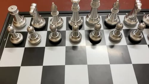 Metallic silver and golden chess pieces arranged on checkered board - Close up shot.