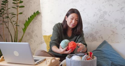 Woman Unraveling Yarn on Sofa at Home