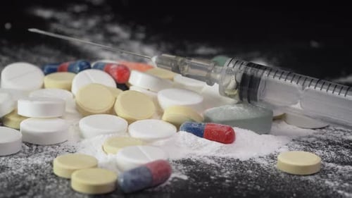 Syringe for injection and white powder cocaine powder and tablets, drugs concept and drug addiction
