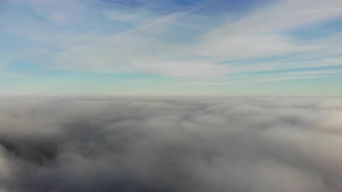 Aerial forward flying shot above and skimming the clouds