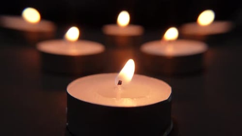 Small burning candles lined up on a black background