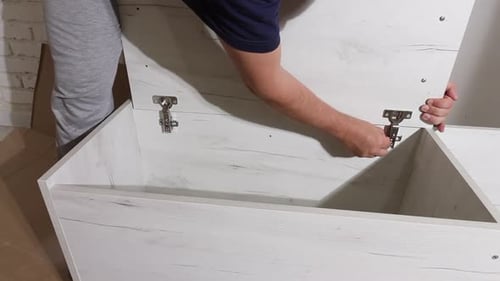 The Man Fixes The Cabinet Door With Screws. The Screwdriver Works. Self Assembly Of Furniture
