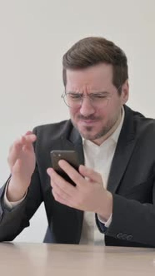 Upset Businessman Reacting to Loss on Smartphone, vertical video