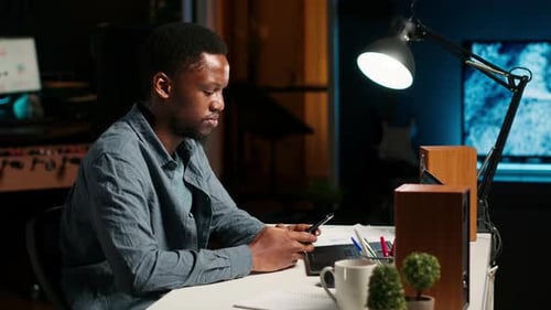 Porträt eines Afroamerikaners, der zu Hause auf seinem Handy scrollt