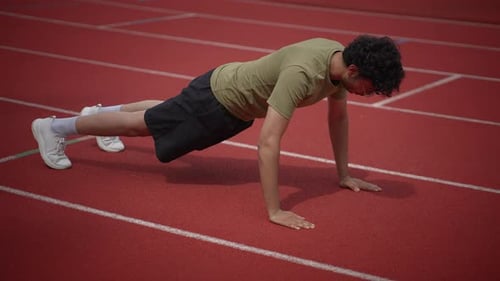 Young Adult Man Doing Pushups on Track
