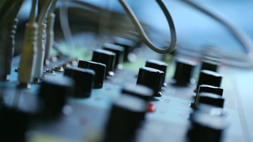 Hand Adjusting Knobs on an Audio Mixer