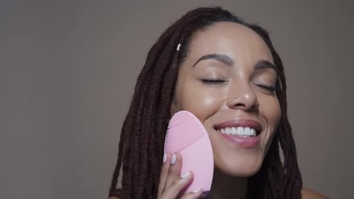 Woman Cleansing Face with Pink Silicone Device
