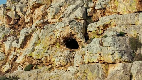 Rückwärtiger Drohnenflug aus einer Höhle auf einem farbenfrohen Felshügel