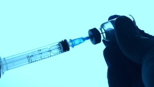 Gloved Hand Draws Vaccine into Syringe from Vial