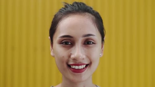 Smiling Woman with Dark Hair Against a Yellow Background