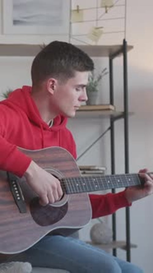 Young Man Plays Acoustic Guitar at Home