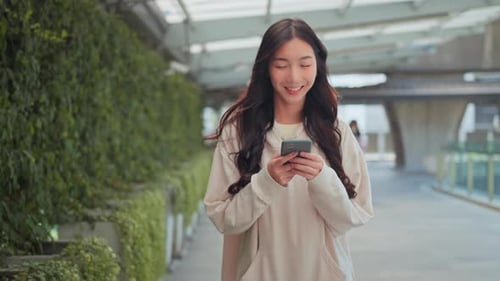Happy young asian woman using mobile phone with chatting online with friend