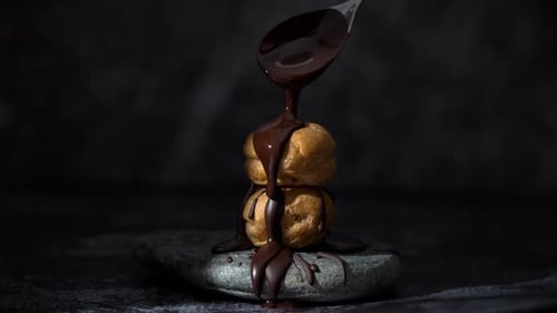 Delicious cream puff sprinkled with melted chocolate. Bakery pastry chef topping liquid chocolate sa