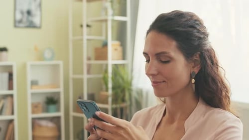 Woman Smiles While Using Cell Phone Indoors