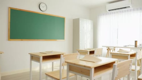 Aufnahme eines leeren Klassenzimmers mit Stühlen unter Schreibtischen in der Grundschule.