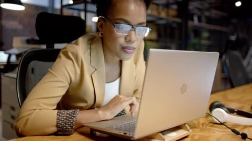 Young African American woman works intently on a laptop in a business office
