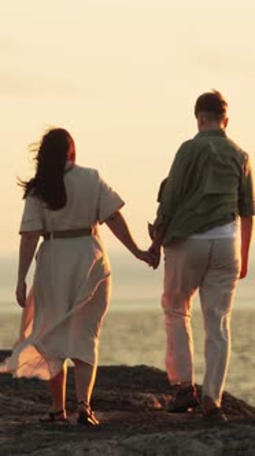 Romantic Couple Walking By the Sea at Sunset