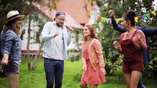 Happy friends dancing groovy music together at summer garden party