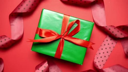 Green gift box with red ribbon 360 degrees rotation, flat lay