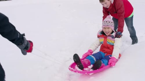 Children enjoy winter fun sledding down snowy hill together on holiday