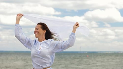 Happy woman with shawl waving in the summer wind on a beautiful beach