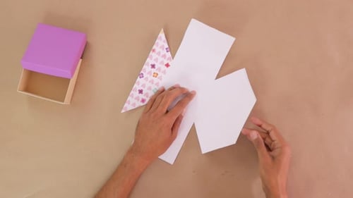 Hands Crafting a Gift Box with Patterned Paper
