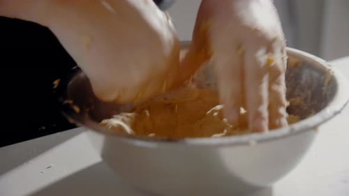 Young Female forming dough in a bowl for a cake in the kitchen at home. Homemade pastry top shot