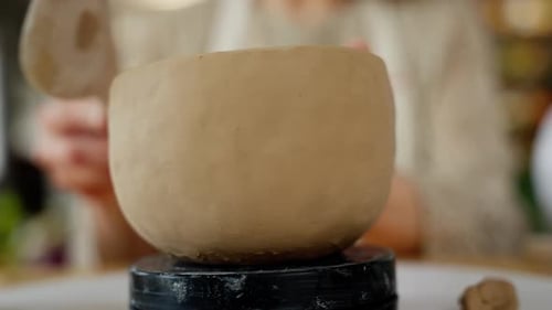 Handmade Ceramic Pot on Pottery Wheel with Defocused Background in Ceramic Workshop