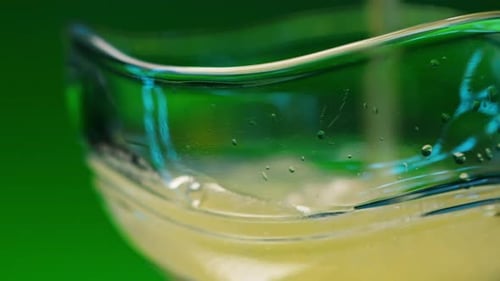 Orange soda is being poured into a glass on blurred colorful background