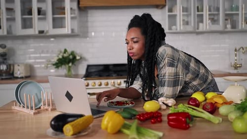 Lunchtime in Home African American Girl Using Laptop Eating Salad in Kitchen Young Adult Black Woman