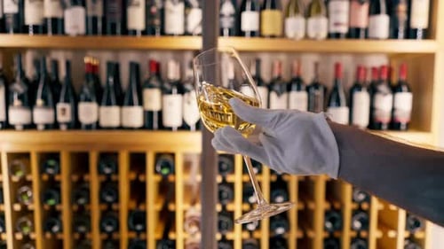 Gros plan d'un verre de vin tenu par un sommelier dans un restaurant italien en arrière-plan