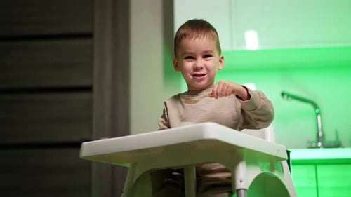 Happy Child Eating Food in a High Chair