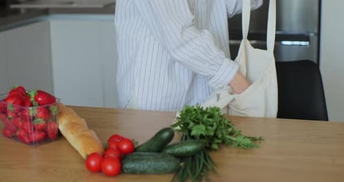 Person Packing Groceries at a Kitchen Table