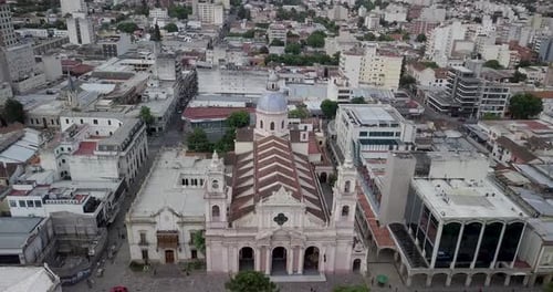 Aerial ascending view above Cathedral Basilica of Salta with views around of city buildings.