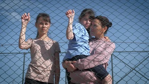 Flüchtlinge hinter dem Zaun.