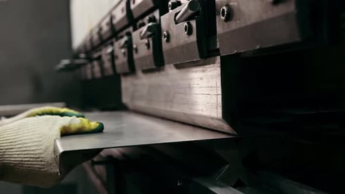 Stahlblecharbeiter in den Händen einer industriellen Biegemaschine, einer Fabrik für die Metallpresse, Industrieausrüstung